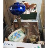 Box containing two oil lamps, one with a blue glass reservoir and brass stem, the other with a white