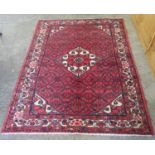 Middle Eastern design red ground carpet with central floral medallion, the borders with stylised