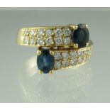 Sapphire and diamond crossover ring with 18ct gold band. Ring size K. Approx weight 6.1 grams. (B.P.