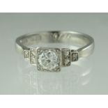 Diamond solitaire ring with stepped diamond set shoulders set in platinum. The central brilliant cut
