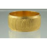 A 22ct gold engraved wedding ring. Width 9mm. Ring size R. Approx weight 9.2 grams. (B.P. 21% + VAT)