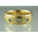 An 18ct gold three stone diamond ring. The three brilliant cut diamonds flush set in an 18ct gold