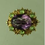 An amethyst and peridot brooch. The oval amethyst approx 16x11mm and surrounded by six peridots in