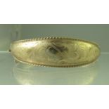 A 9ct gold hinged and engraved bangle. Approx weight 15.7 grams. (B.P. 21% + VAT)