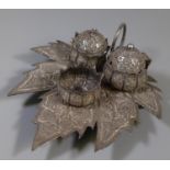 White metal novelty three piece cruet set, the base in the form of a leaf with floral and other