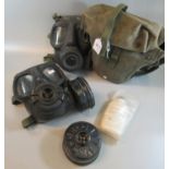 Two vintage military gas masks, one contained in a military canvas satchel. (B.P. 21% + VAT)