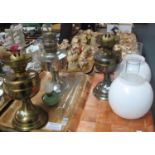 Two trays with three brass and white metal oil lamps, with three glass chimneys and two opaline