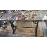 Victorian cast iron garden table, the top decorated with assorted postcards and scrap cuttings. (B.