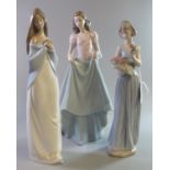 Three Nao Spanish porcelain figurines of young girls with a basket of flowers, crinoline dress