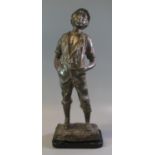 Patinated white metal plaster filled figure of a young country boy on naturalistic base,