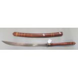 An Indonesian or Siamese steel bladed ceremonial or dance sword with cane bound scabbard and