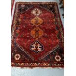 Middle Eastern hand woven red ground carpet with four geometric and foliate medallions. 262x174cm