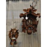 Carved, probably walnut Cuckoo Clock with stags head, animals and rifles on chain with cone waits,