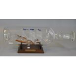 Glass ship in a bottle on wooden stand 'Mayflower'. (B.P. 21% + VAT)