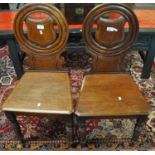 Pair of Victorian mahogany hall chairs, the circular moulded backs inset with carved shield, the