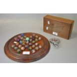 Solitaire wooden and moulded games board comprising a collection of vintage hand made marbles,