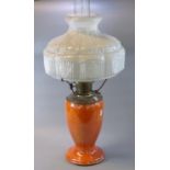 Early 20th Century oil burner lamp having white opaline glass shade above an orange porcelain