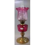 Early 20th Century double oil burner lamp, having frosted cranberry glass shade, above a cranberry