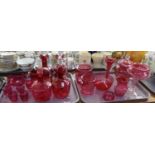 Two trays of cranberry glass items to include: four decanters with stoppers, shot glasses, liqueur