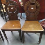 Pair of Victorian mahogany hall chairs, the circular moulded backs inset with carved shield, the