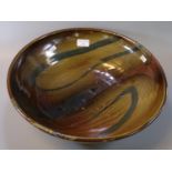 Large art pottery circular bowl, brown glazed with swirl decoration. Indistinct impressed mark to