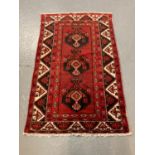 Red ground Baluchi Nomadic rug, having three central stylised floral medallions with decoration of