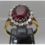 18ct gold ring set with a large oval red stone surrounded by diamonds. Ring size N. Approx weight