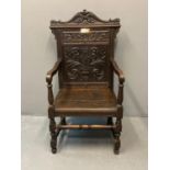 Early 20th Century carved and stained oak Eisteddfod chair, the carved back with dolphin, vase and
