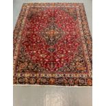 Red ground Persian Mashad carpet with floral medallion design. 295x223cm approx.