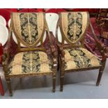 Pair of ornately carved Empire style armchairs, the carved and upholstered shield shaped backs
