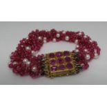Multi strand ruby bead and pearl bracelet with yellow metal clasp set with nine rubies. Approx