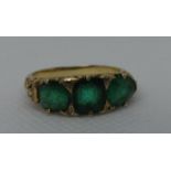 A three stone emerald ring set in yellow metal. Ring size M & 1/2. Approx weight 4.8 grams. (B.P.