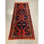 Red and navy ground Hussain runner with double medallion design. 305x125cm approx. (B.P. 21% + VAT)