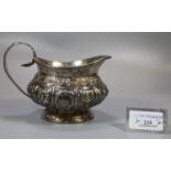 19th century silver helmet shaped single handed jug, having repousse decoration of flowers and