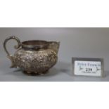 White metal probably Indian baluster single handled cream jug with repoussé floral and foliate