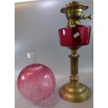 Early 20th Century double oil burner lamp, having cranberry glass etched globular shade, above a