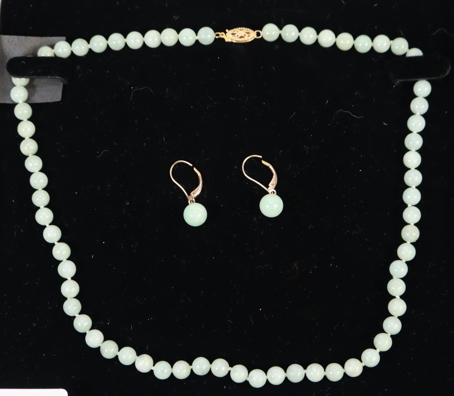 An oriental design necklace of green graduated hardstone beads with a pair of matching earrings.