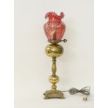 A gilt metal table lamp with a Bohemian red glass shade