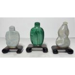 THREE CHINESE SNUFF BOTTLES ON WOODEN STANDS, QING DYNASTY (1644-1911)