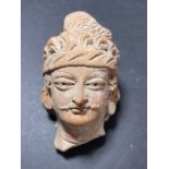 A TERRACOTTA HEAD FRAGMENT, POSSIBLY GANDHARA OR LATER
