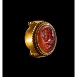 A GREEK GOLD AND CARNELIAN RING OF AN ATHLETE WITH A DOLPHIN