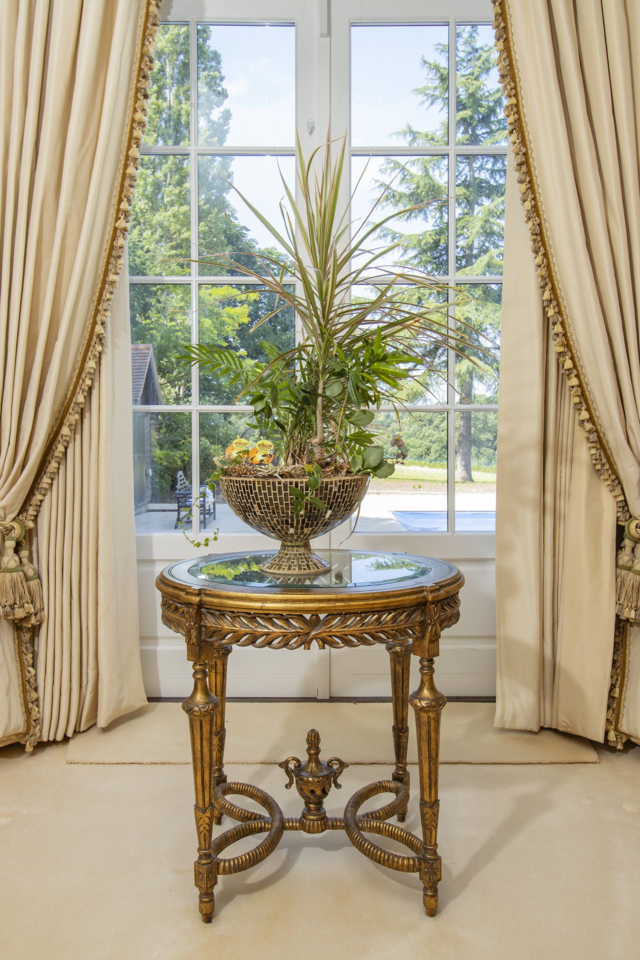 A Louis XVI style round accent mirror plate top side table with a pierced apron, above fluted