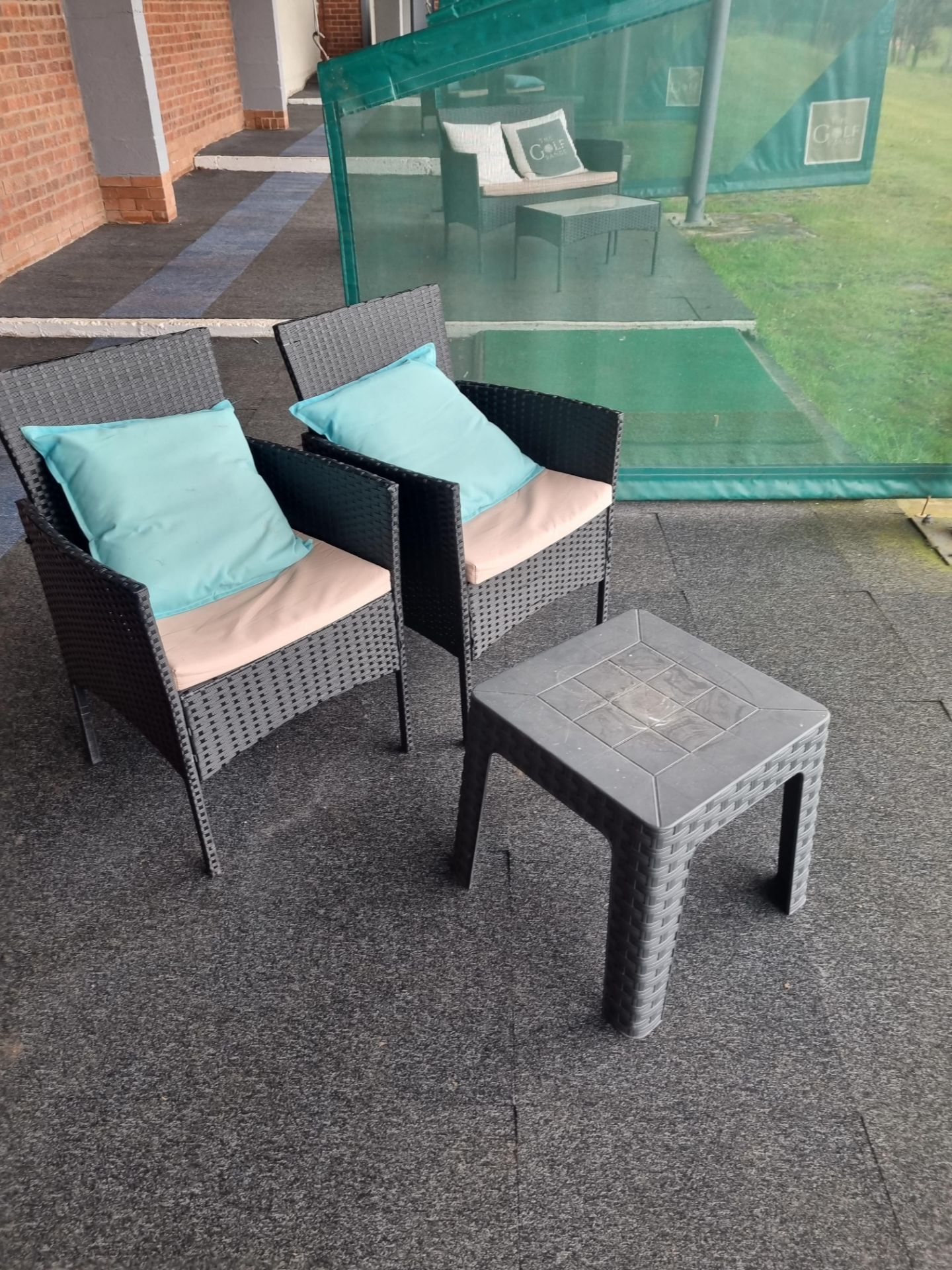 A pair of polyrattan armchairs and a small side table