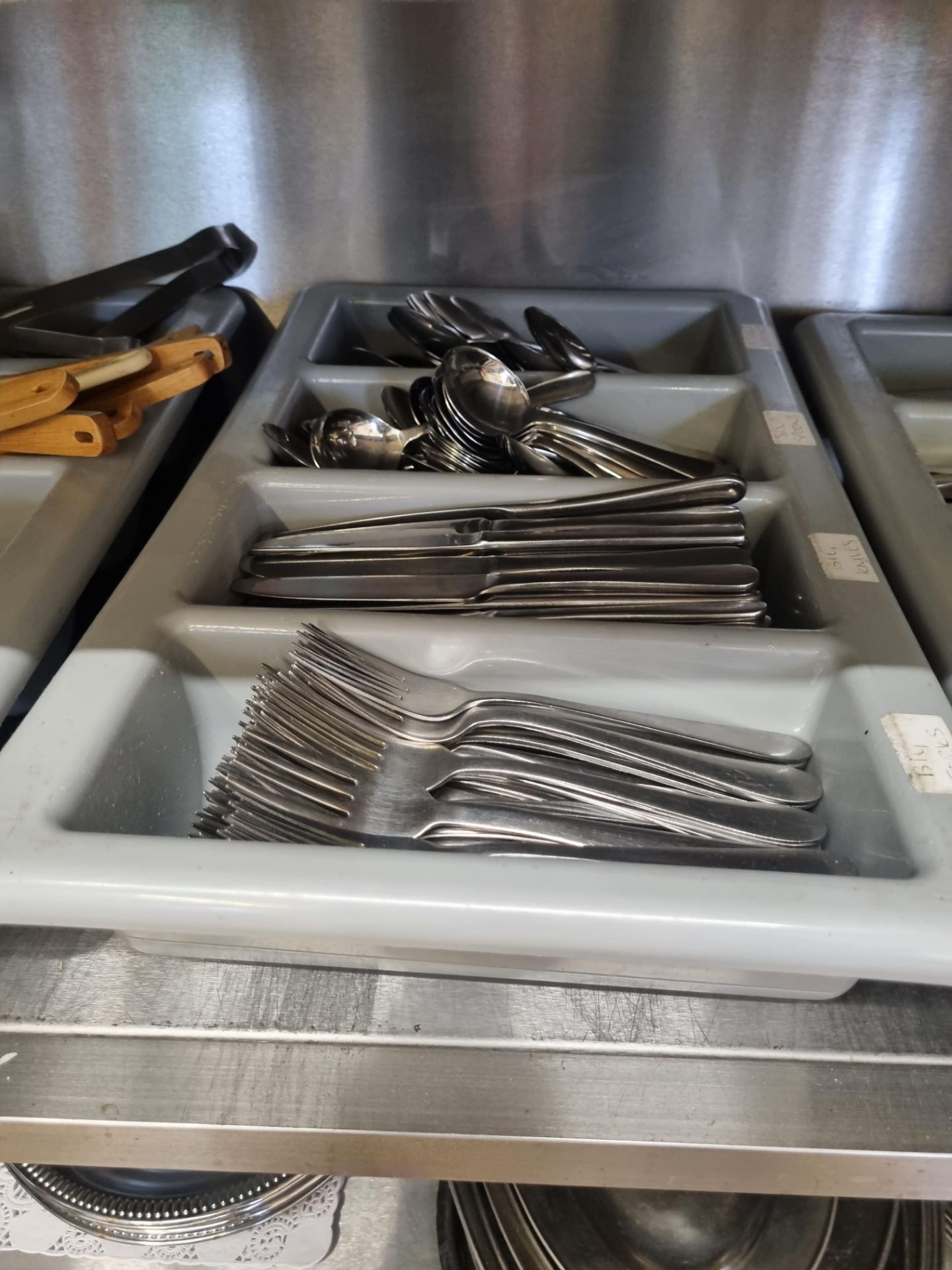 A large quantity of stainless steel cutlery within trays as found