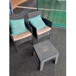 A pair of polyrattan armchairs and a small side table