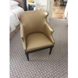 A Modern Wing Back Accent Chair Upholstered In Gold Leather With Pin Stud Detail On Dark Solid