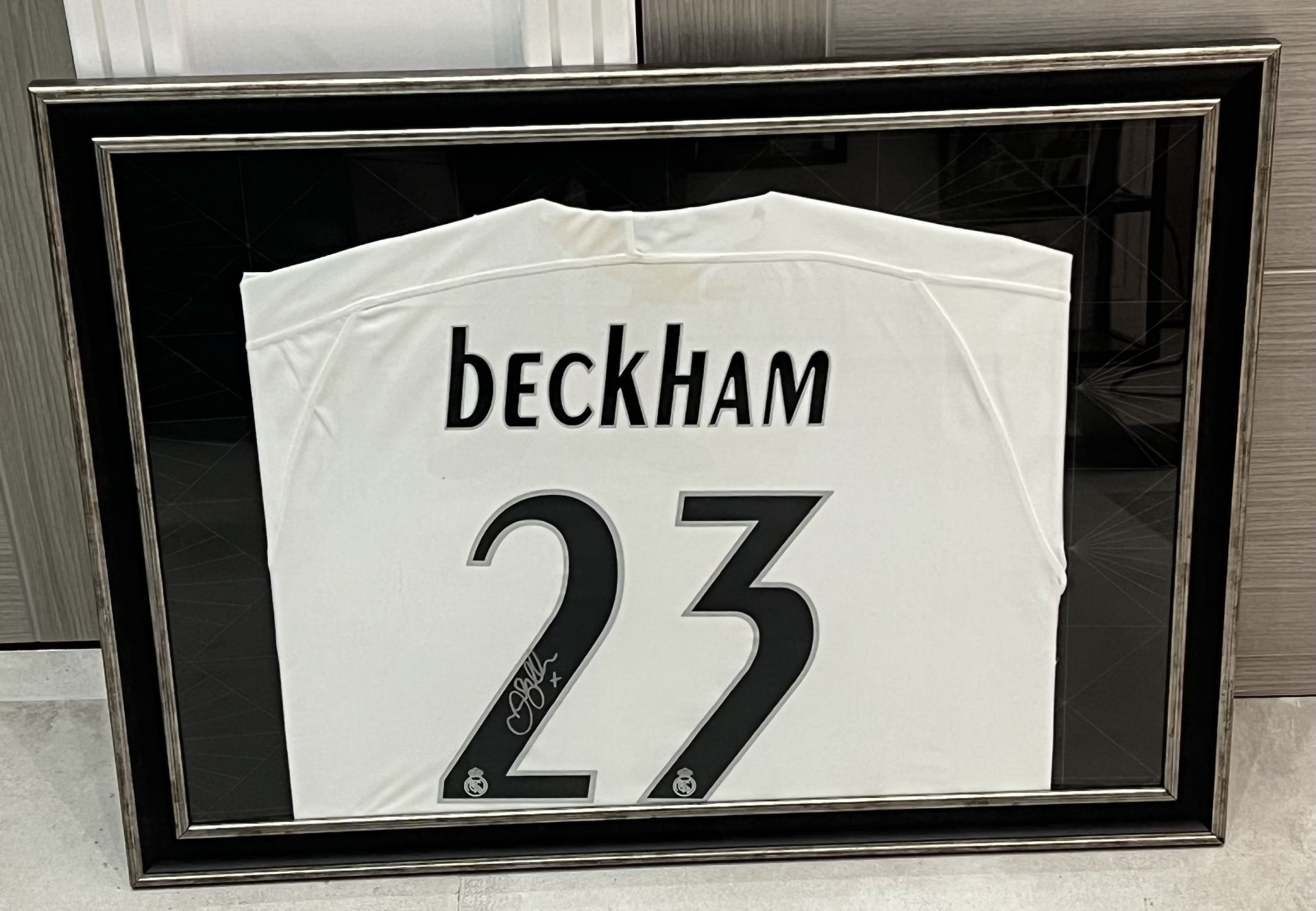 Hand signed Real Madrid football shirt signed by David Beckham presented within a silver and black