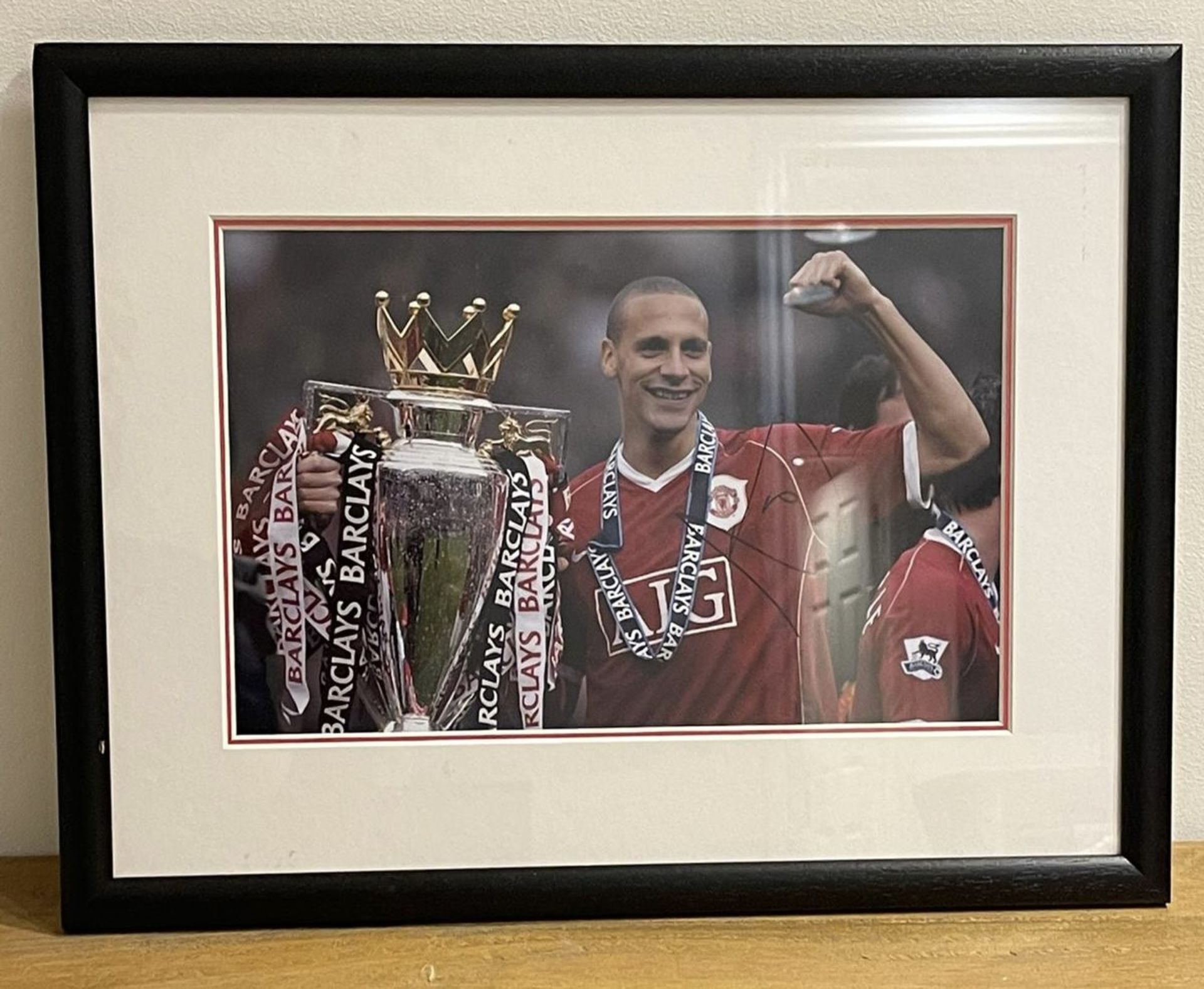 Hand signed Rio Ferdinand photograph featuring him with title winning trophy for Manchester United