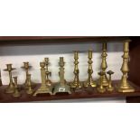 SHELF OF BRASS CANDLESTICKS, (8)