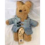 A TEDDY BEAR WITH A PADDINGTON BEAR LABEL ATTACHED